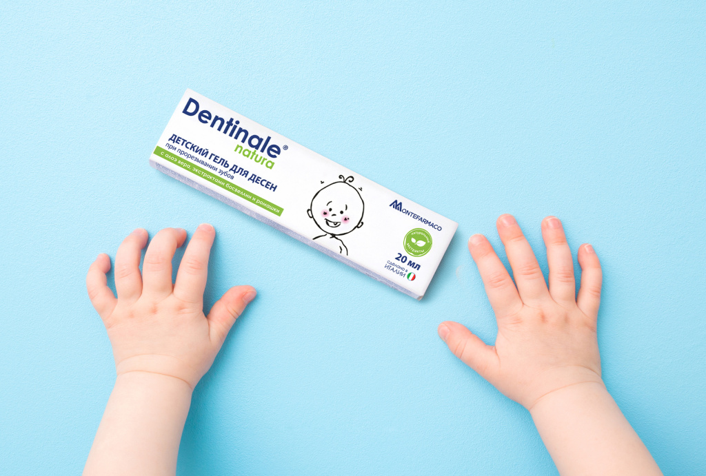Детский гель для десен Dentinale natura при прорезывании зубов — упаковка средства на голубом фоне рядом с ручками малыша